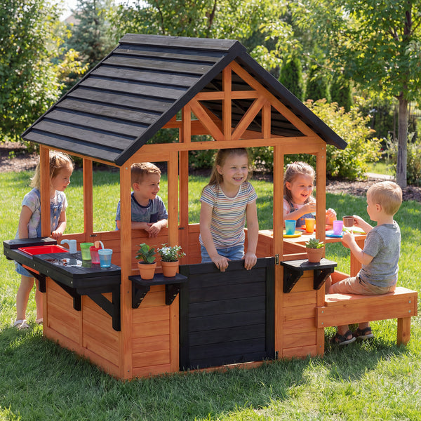 Wooden playhouse for children aged 3 to 8, with a table, benches, a sink, windows, and flower box holders, brown.